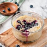 blueberry mug cake in clear glass jar on cutting board