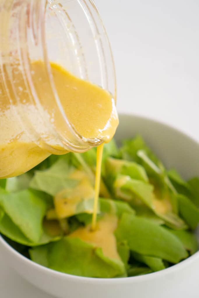 pouring dijon vinaigrette on salad