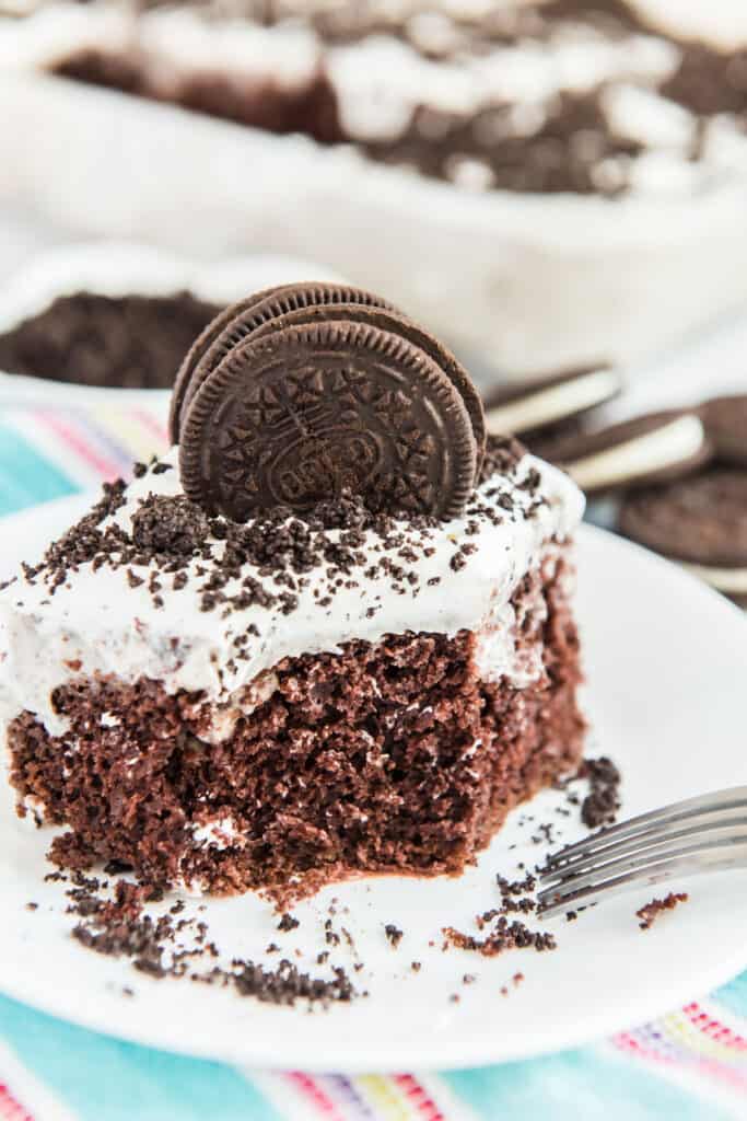 oreo poke cake on white plate with colorful napkin underneath