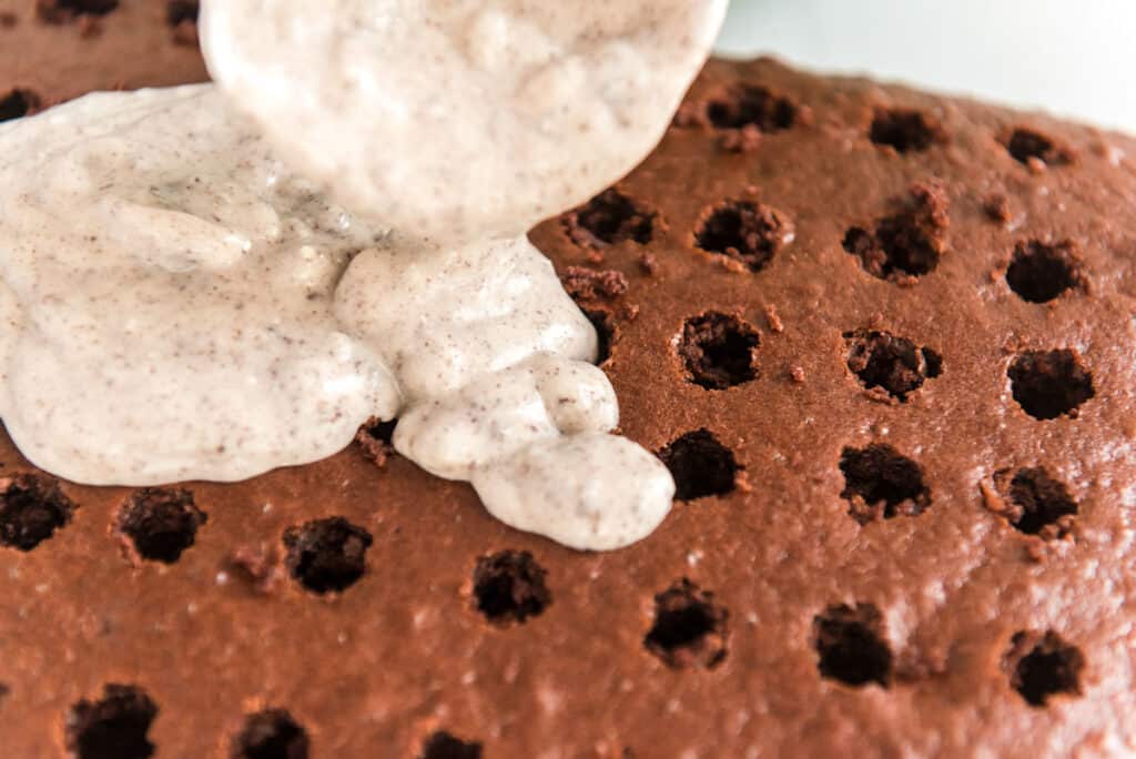 pouring oreo pudding over chocolate cake with holes poked in it for oreo poke cake