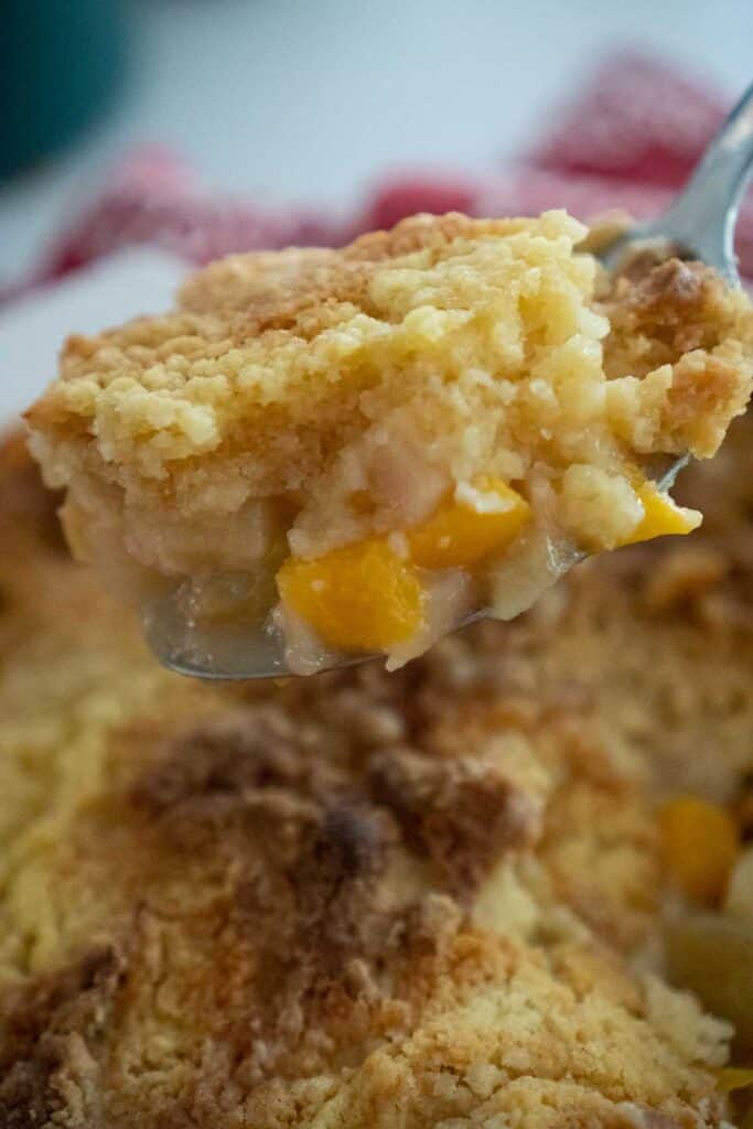 fruit cocktail dump cake in a spoon over casserole dish