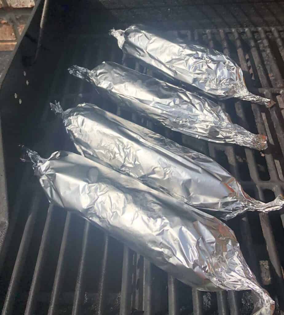 foil wrapped corn on the cob on the grill