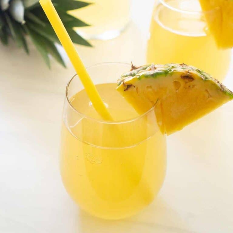pineapple rum punch in stemless glass with slice of pineapple and yellow straw