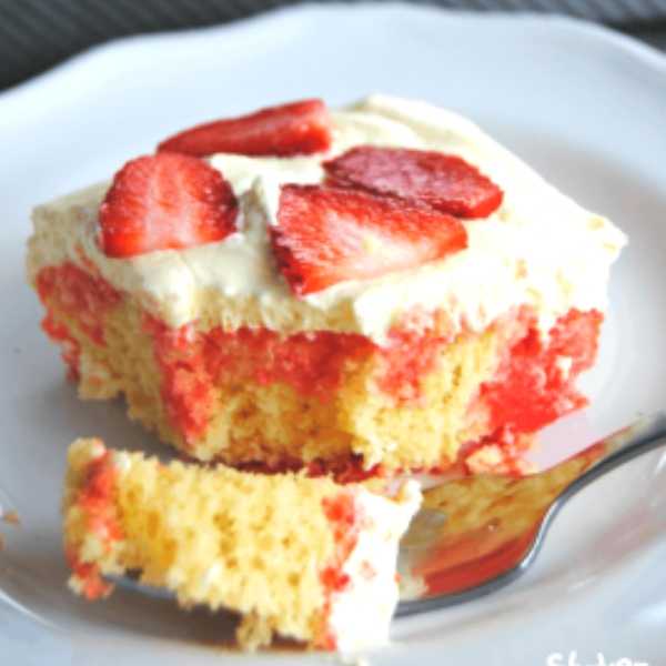 lemon strawberry poke cake on white plate topped with sliced strawberries