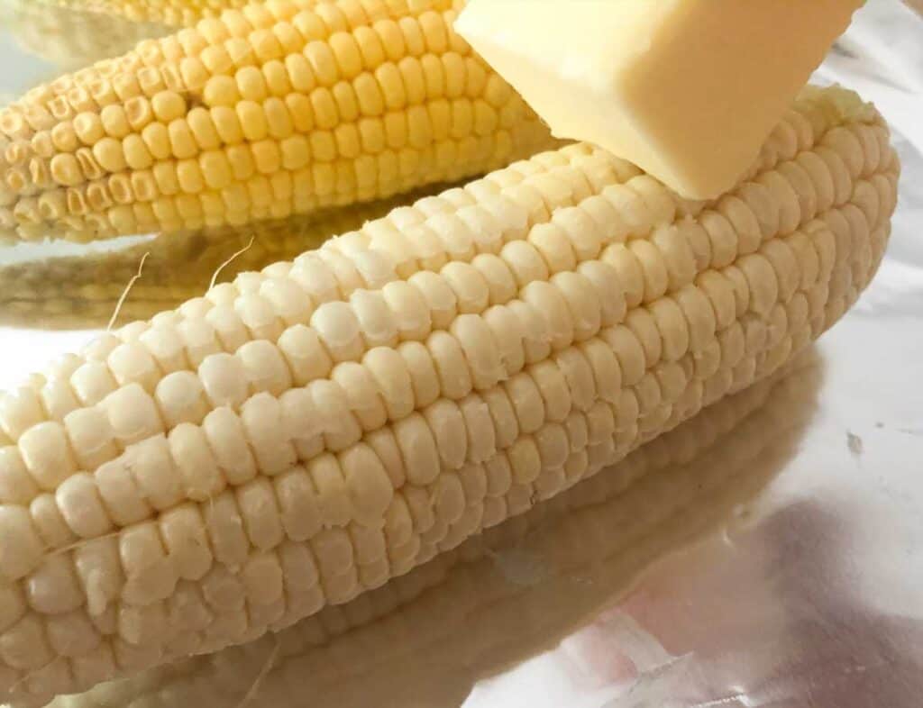 rubbing stick of butter over corn on the cob before grilling in foil