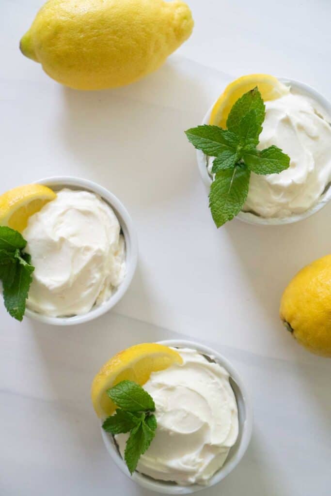 overhead view of lemon cheesecake mousse in white ramekin garnished with lemon slice and mint sprig