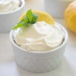 close up lemon cheesecake mousse in white ramekin garnished with lemon slice and mint sprig