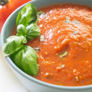 fresh tomato marinara sauce with basil leaves in grey bowl