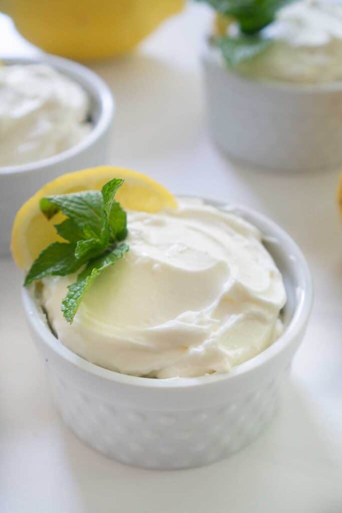 lemon cheesecake mousse in white ramekin garnished with lemon slice and mint sprig