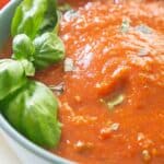 text reading fresh tomato marinara over close up of bowl of tomato sauce with basil leaf garnish