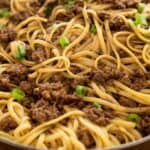 text reading 15 minute mongolian noodles over close up photo of mongolian noodles in skillet with chopped green onion