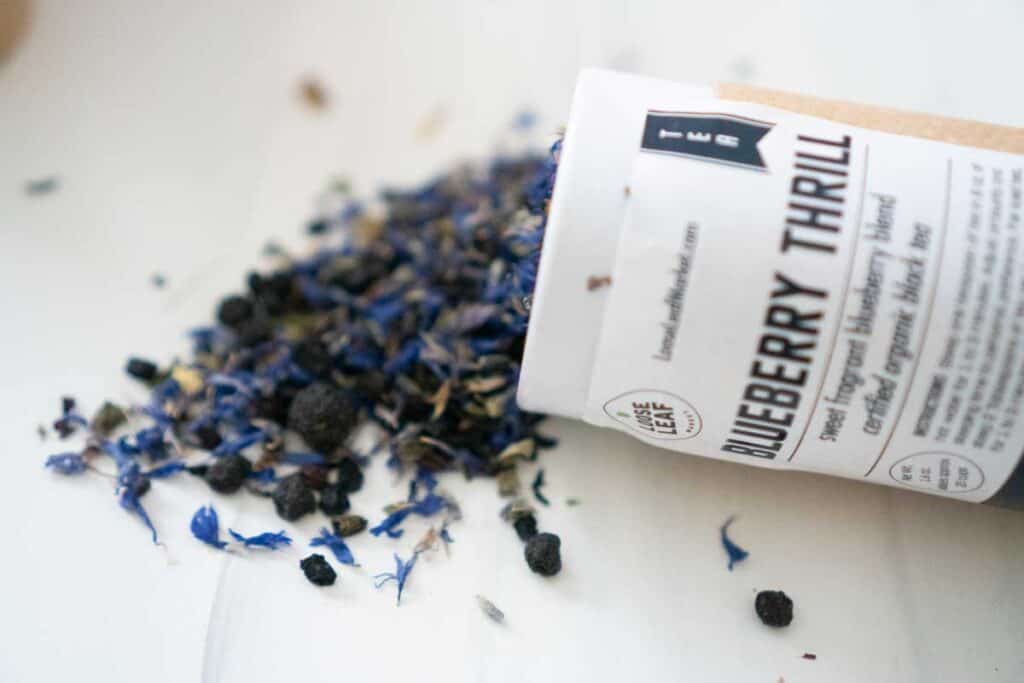 blueberry thrill loose leaf tea container on its side with tea leaves spilling out