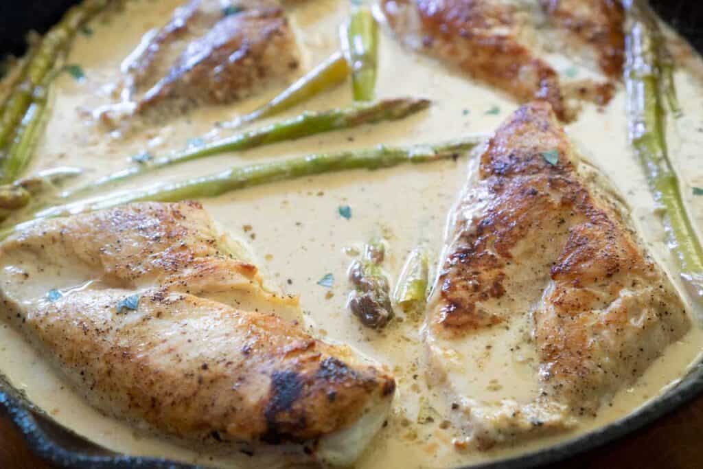 lemon butter chicken with asparagus in cast iron skillet