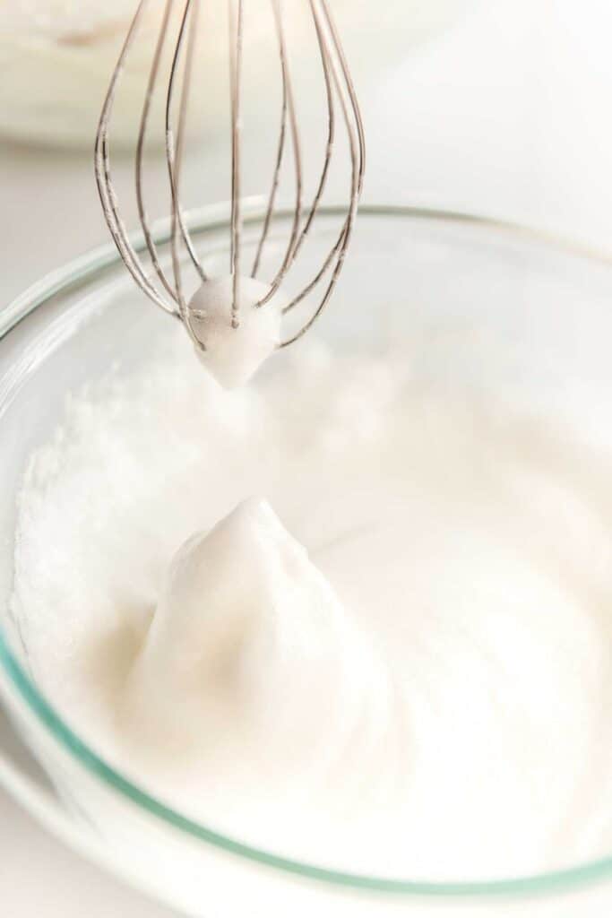 whipped egg whites in glass bowl with mixer