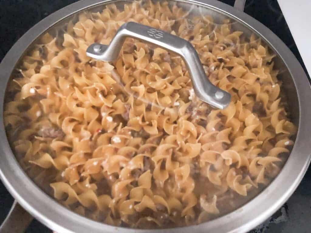 creamys ausage pasta cooking in covered pan