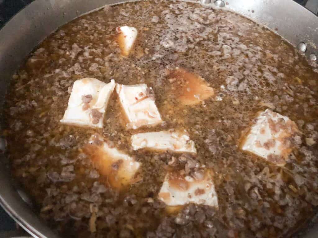 ground sausage with brotha nd chunks of cream cheese in pan