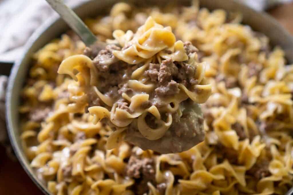 ground beef stroganoff in spoon held over pan