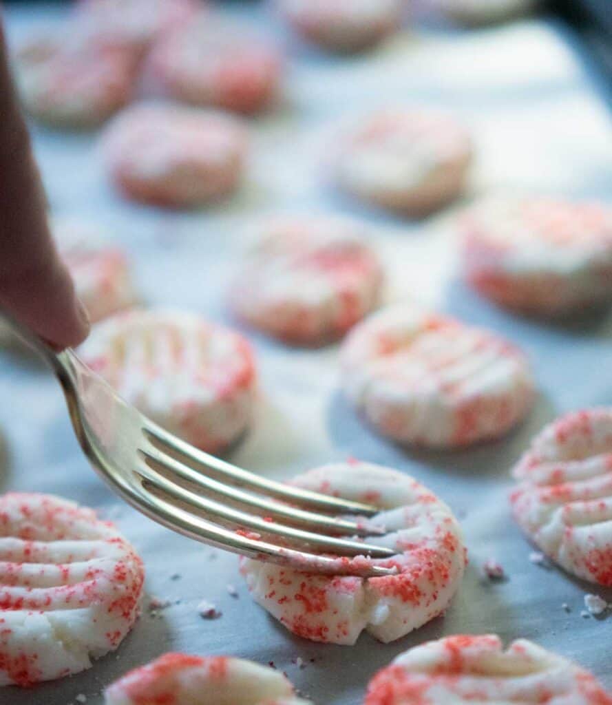 fork pressing into cream cheese mint on baking sheet