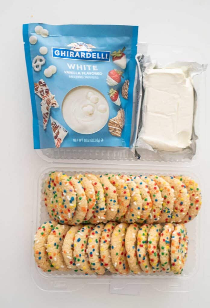 sugar cookies, cream cheese, and melting white chocolate on white countertop