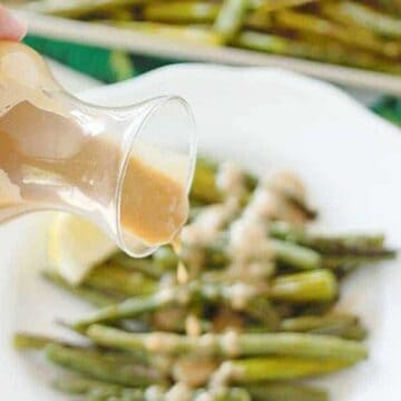 pouring dijon sauce over asparagus