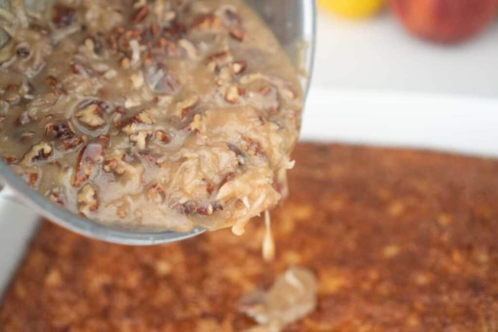 pouring coconut topping on cake