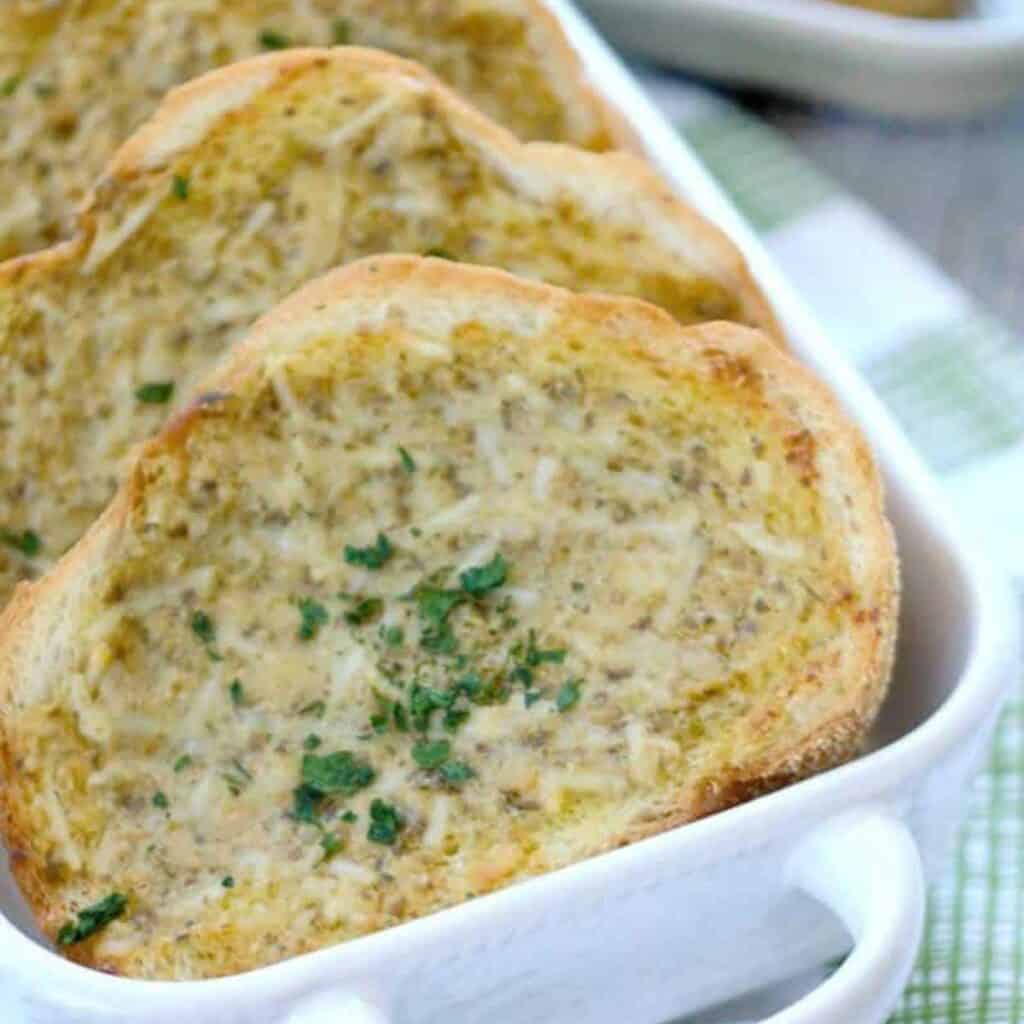 sliced of pesto garlic bread in white dish