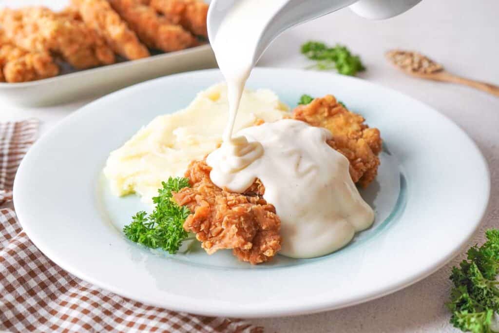 pouring gravy over chicken fried chicken