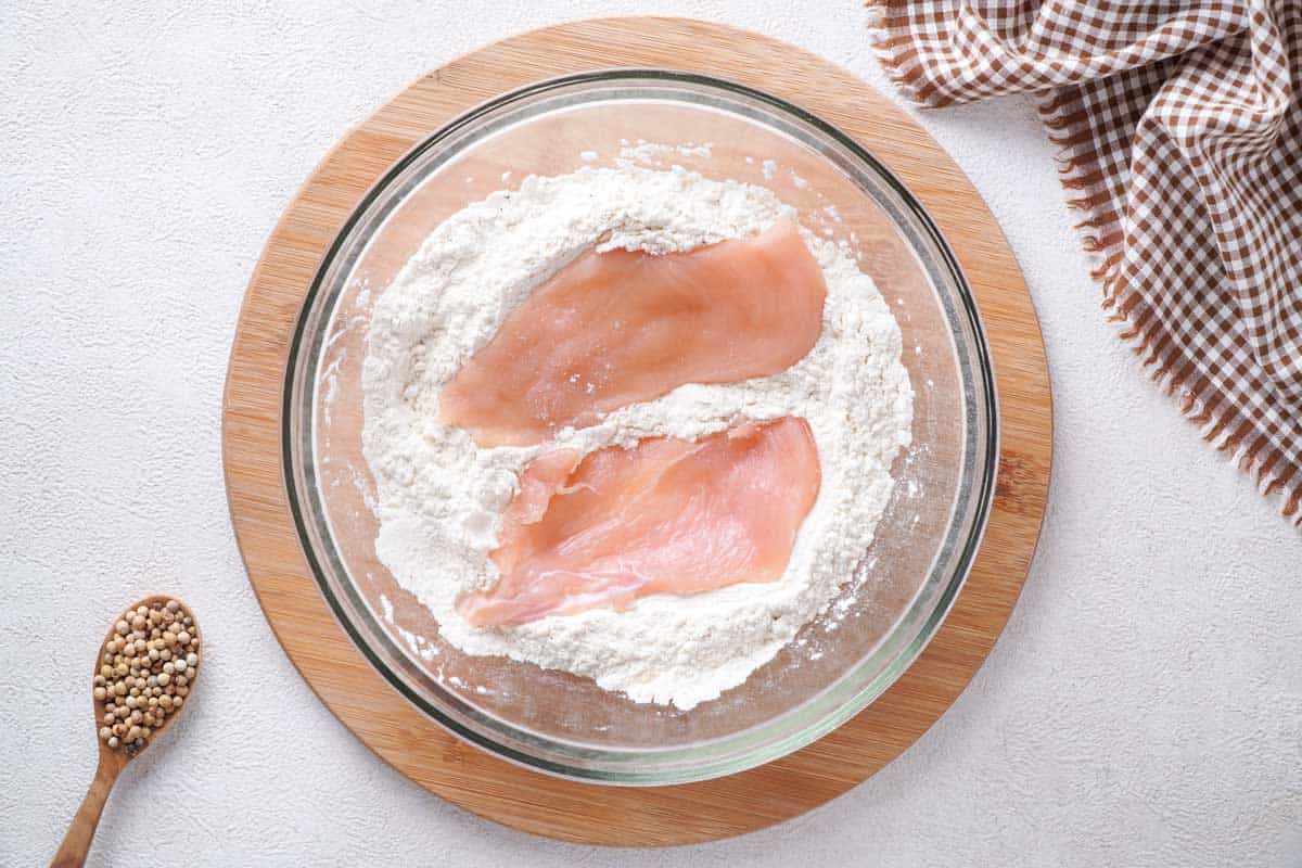 chicken breasts in flour in glass bowl