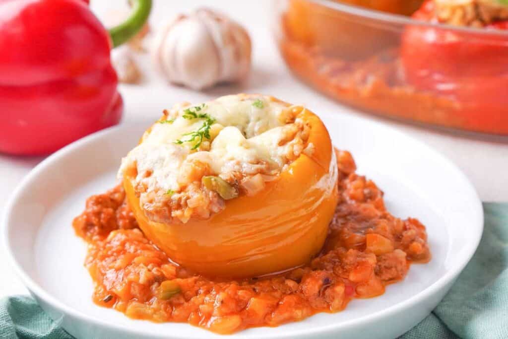 orange bell pepper stuffed with meat and rice on white plate