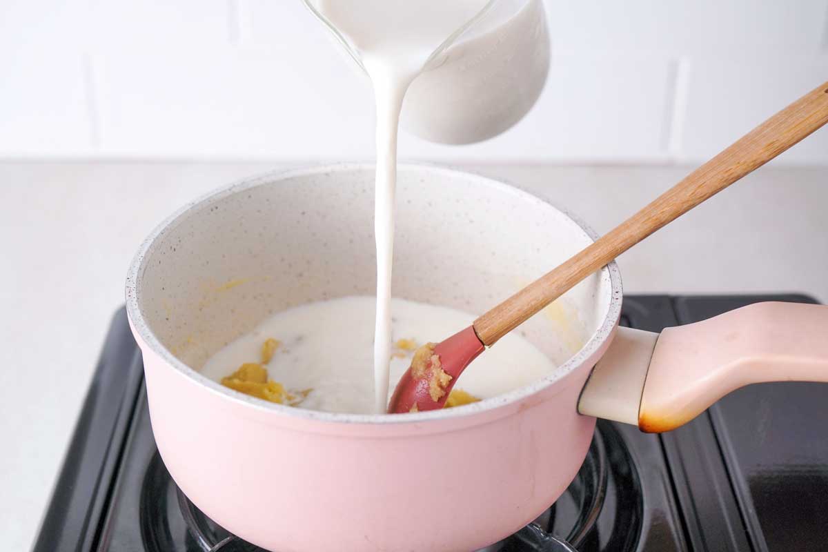 milk pouring into a saucepan with spoon