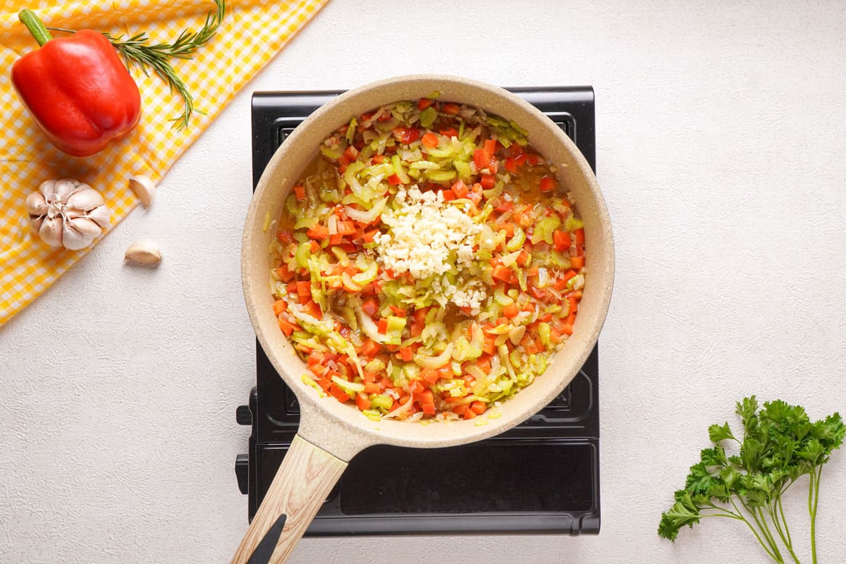 adding garlic to cooked veggies in pan