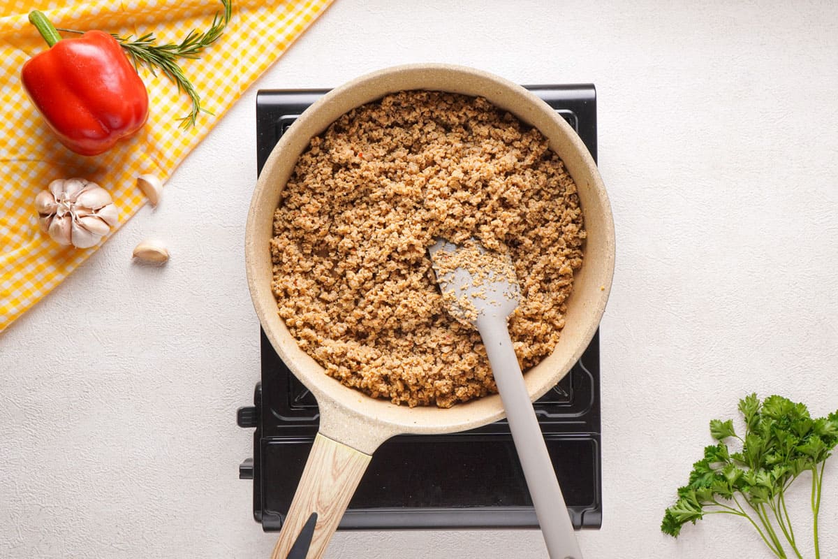 overhead view of browning sausage in skillet with spatula
