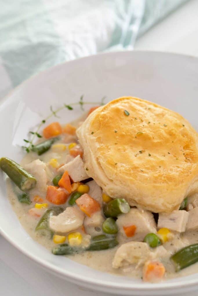 chicken pot pie casserole serving in white bowl with biscuit on top