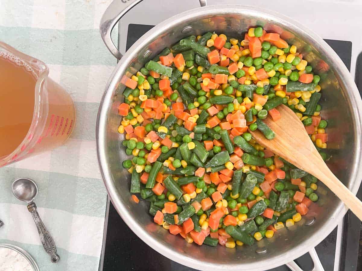 stirring mixed vegetables in skillet