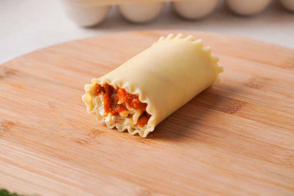 single lasagna roll up on wood cutting board