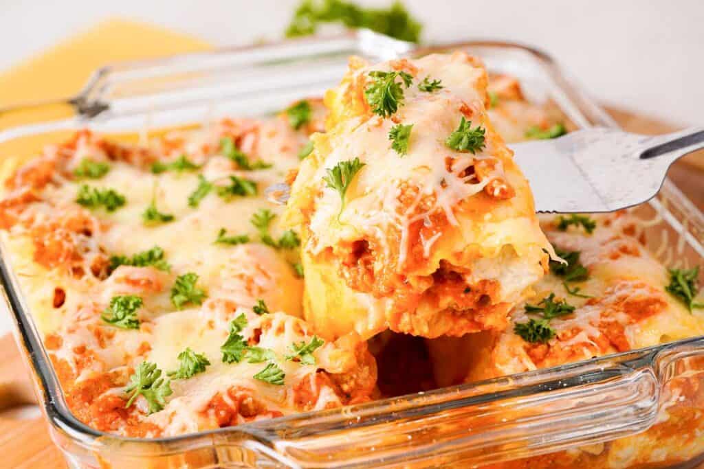 spatula lifting lasagna roll up from baking dish