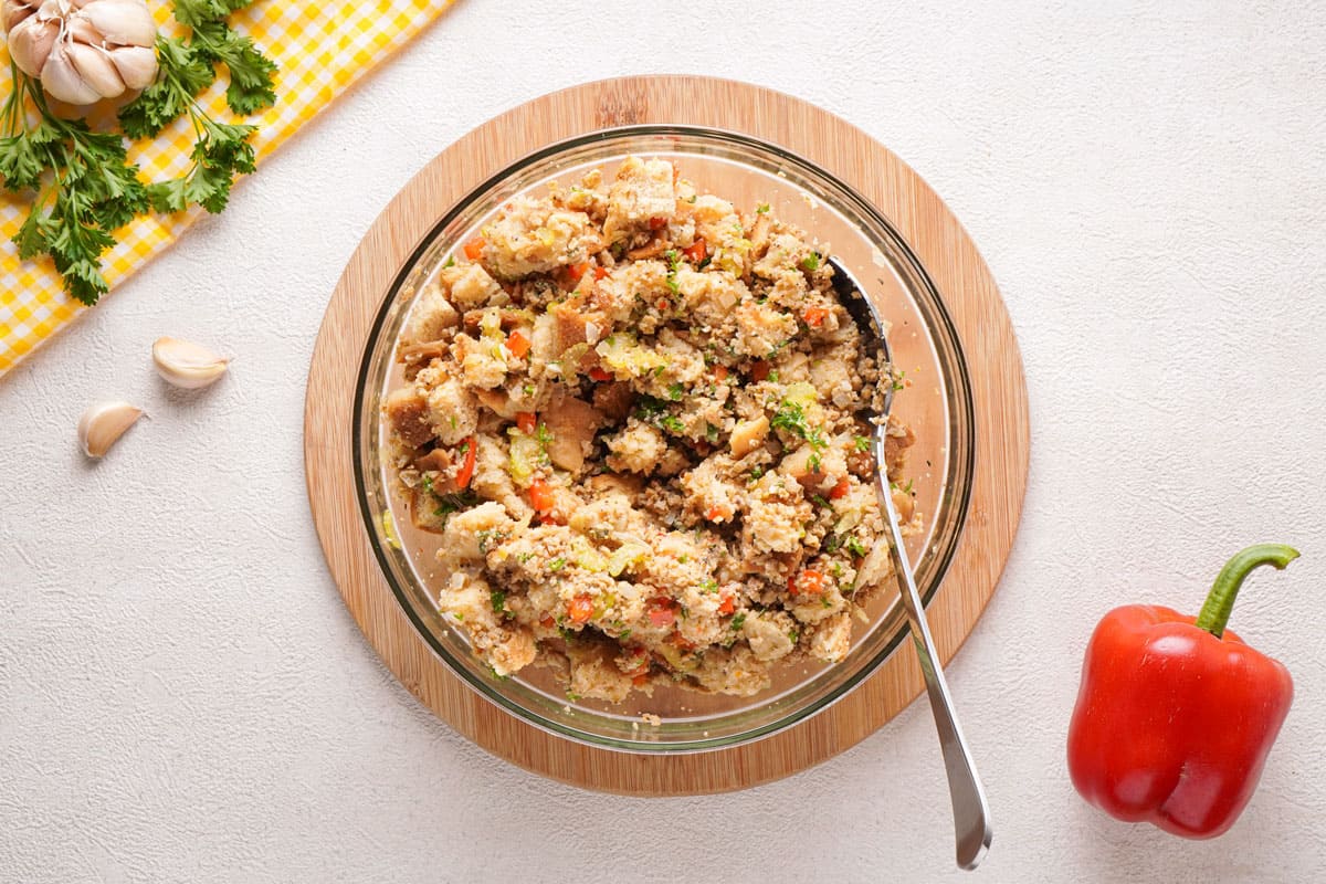 stirring together sausage stuffing in glass bowl