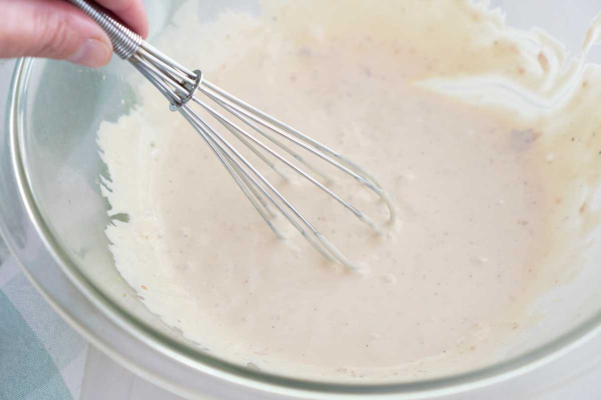 whisk stirring homemade caesar salad dressing