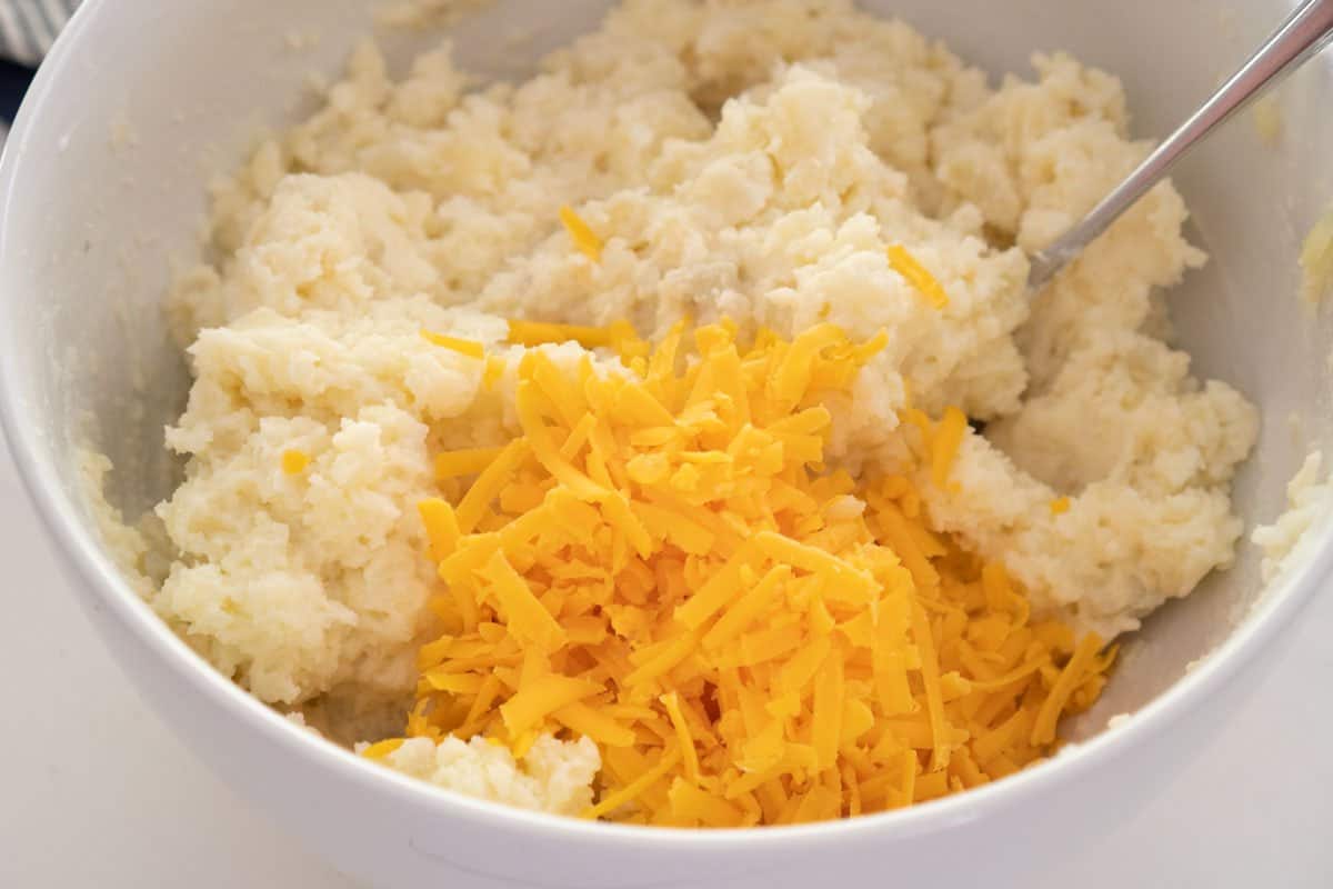 cheddar cheese and mashed potatoes in large white bowl