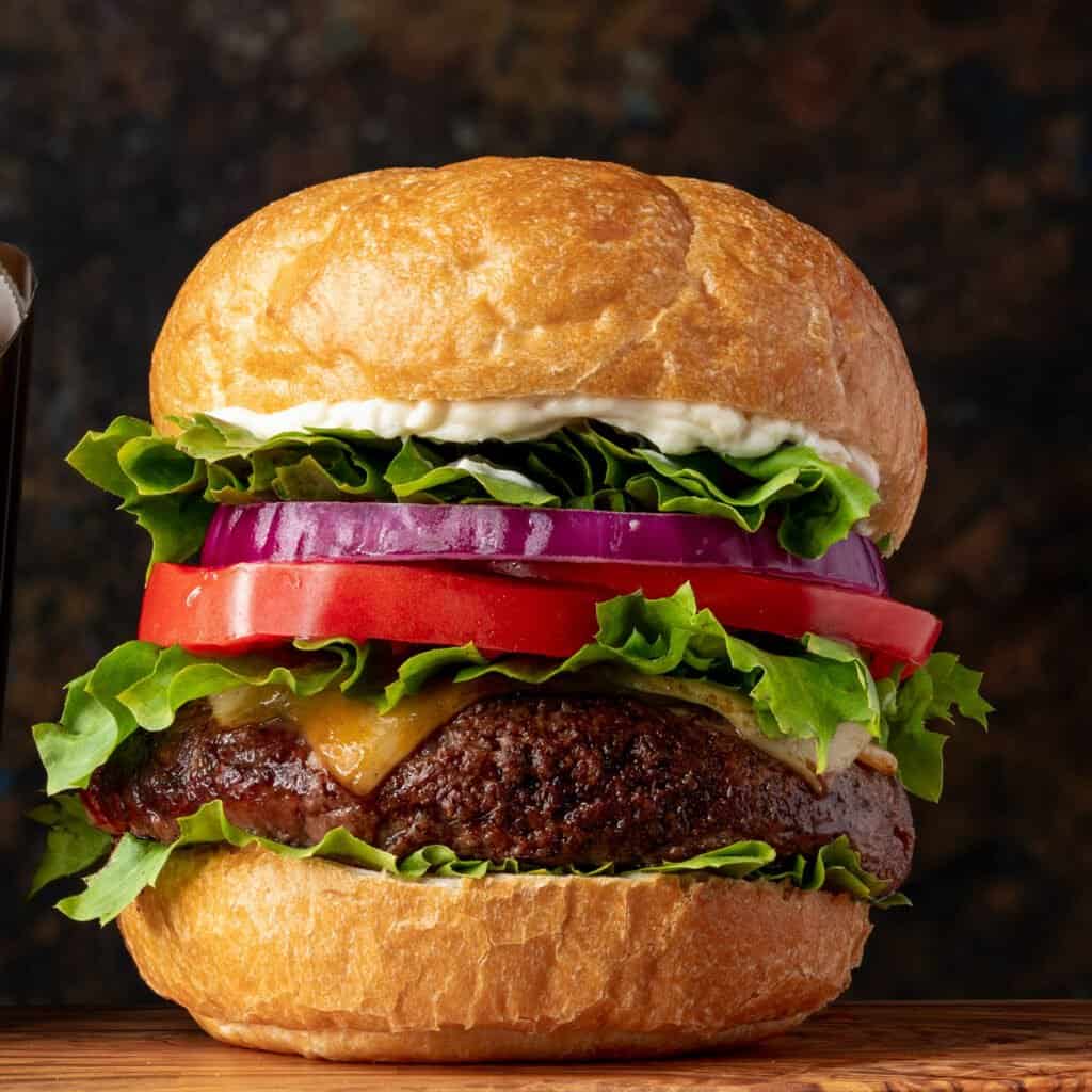 close up of hamburger with cheese, tomato, onion, and lettuce