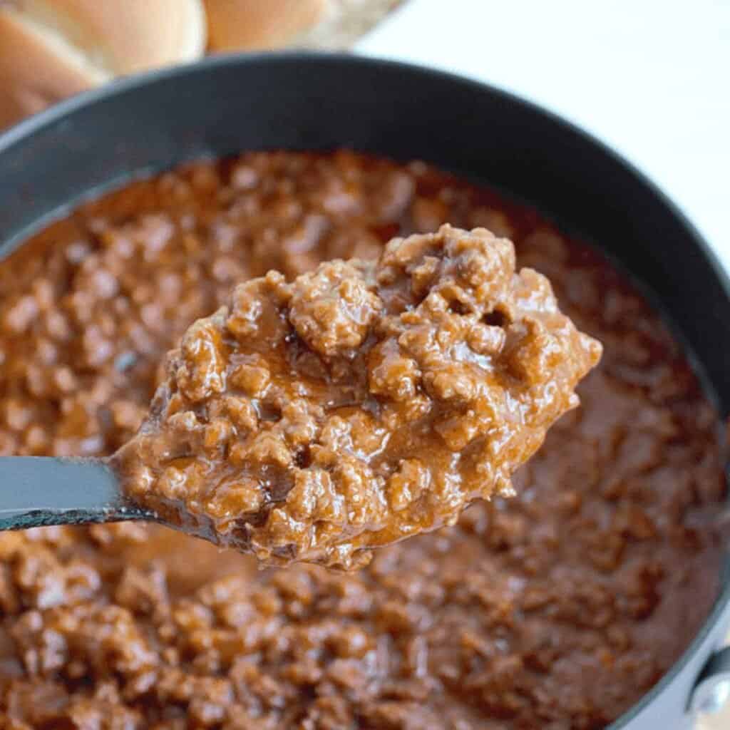 spoon full of sloppy joe meat held over skillet of sloppy joes