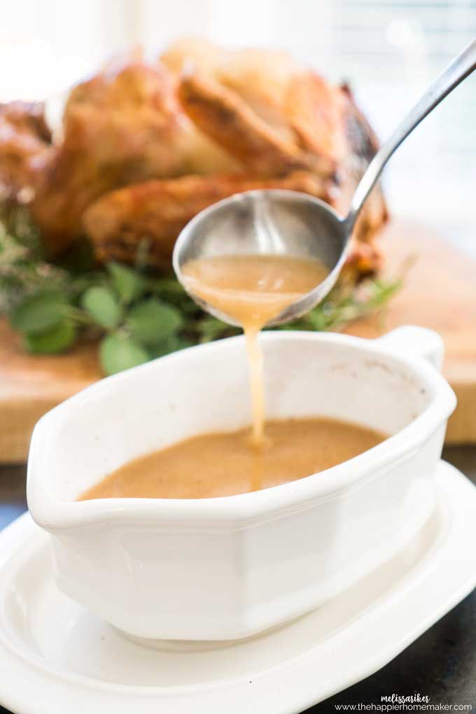 ladle pouring gravy into gravy boat with turkey in the background
