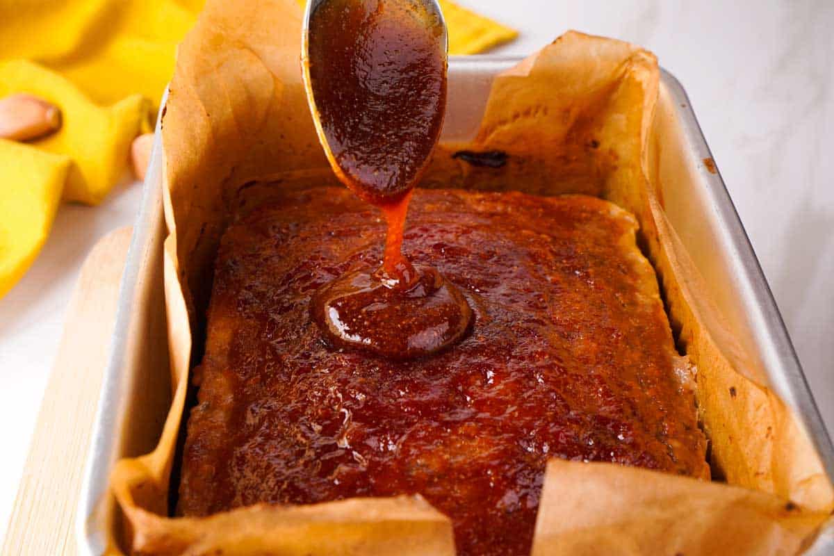 spoon pouring glaze over meatloaf