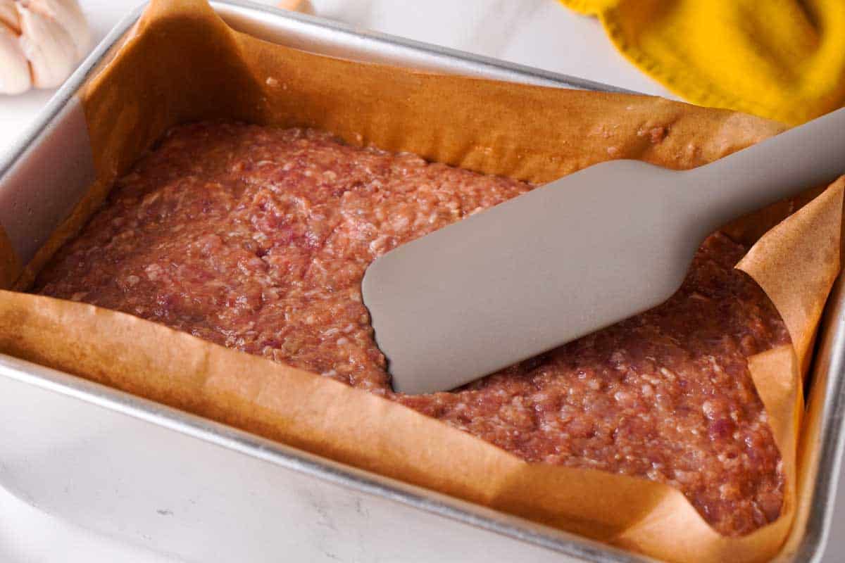 pushing meatloaf mixture into pan before baking