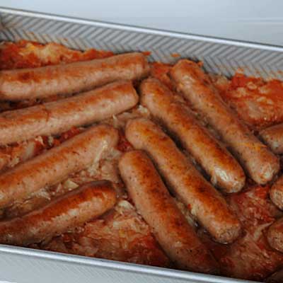 baked brats and sauerkraut in metal baking dish