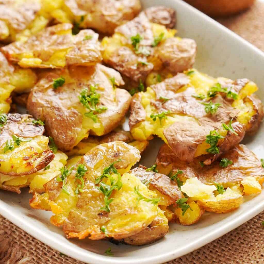 smashed baby potatoes on a white platter