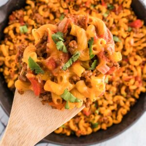wooden spoon of taco macaroni held over skillet