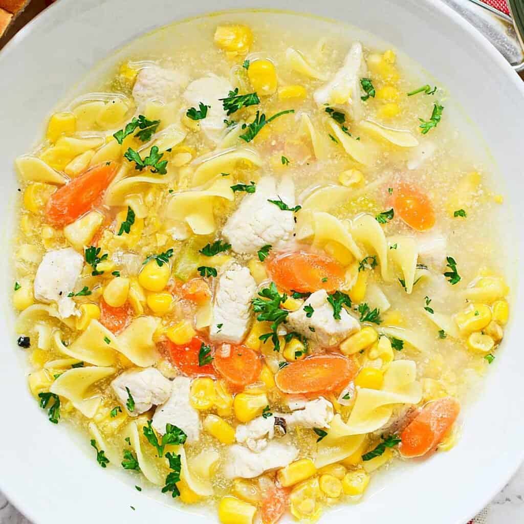 overhead view of chicken corn noodle soup in white bowl