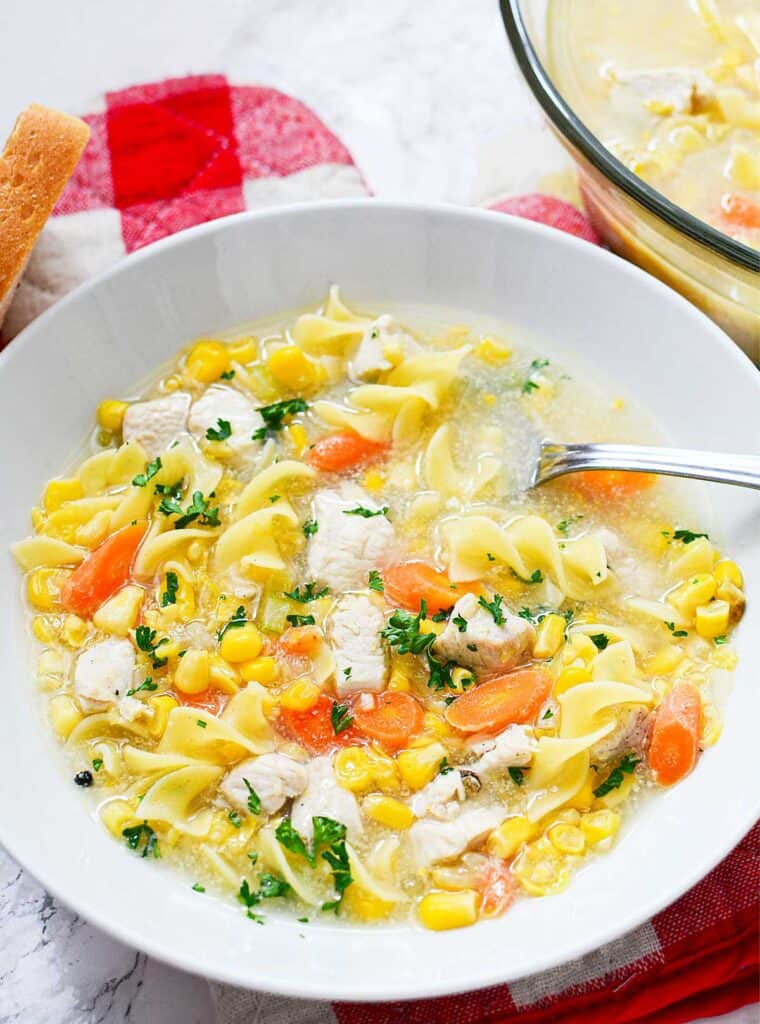 white bowl with chicken corn noodle soup and spoon