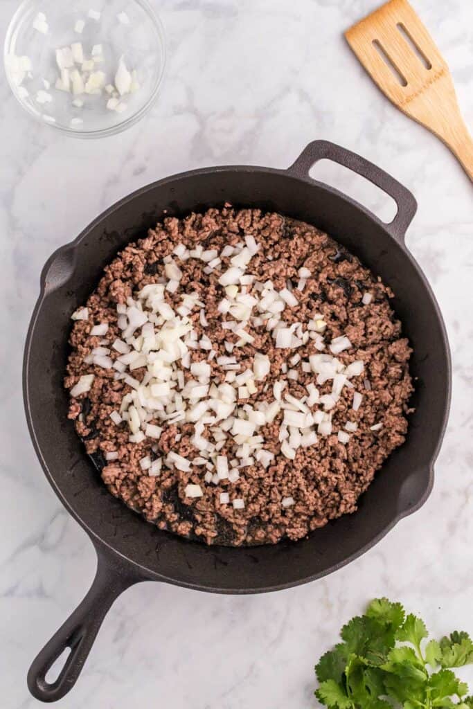 skillet with browned ground beef and diced onion
